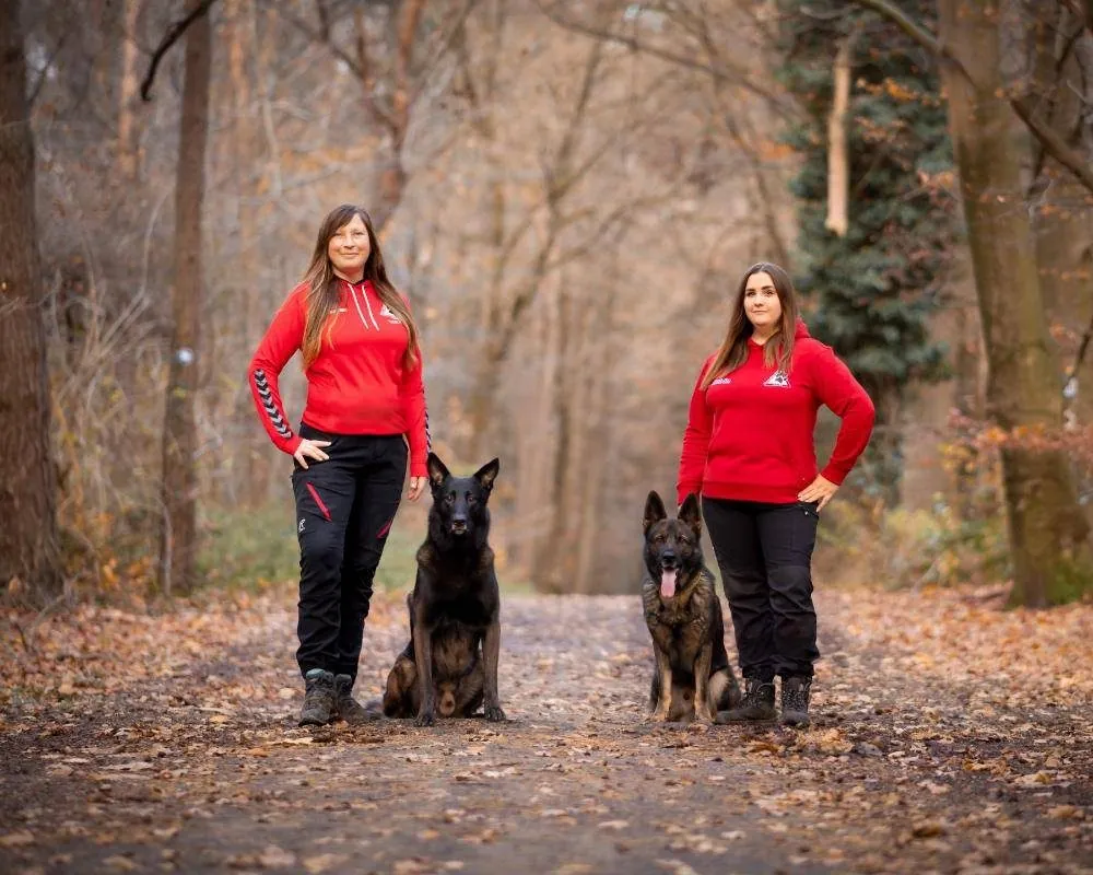 Lynn und Katrin mit ihren Schäferhunden auf einem Waldweg im Herbst