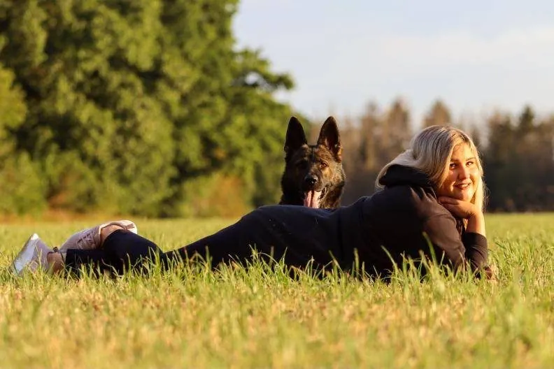 Katrin liegt mit ihrem Schäferhund in der Wiese